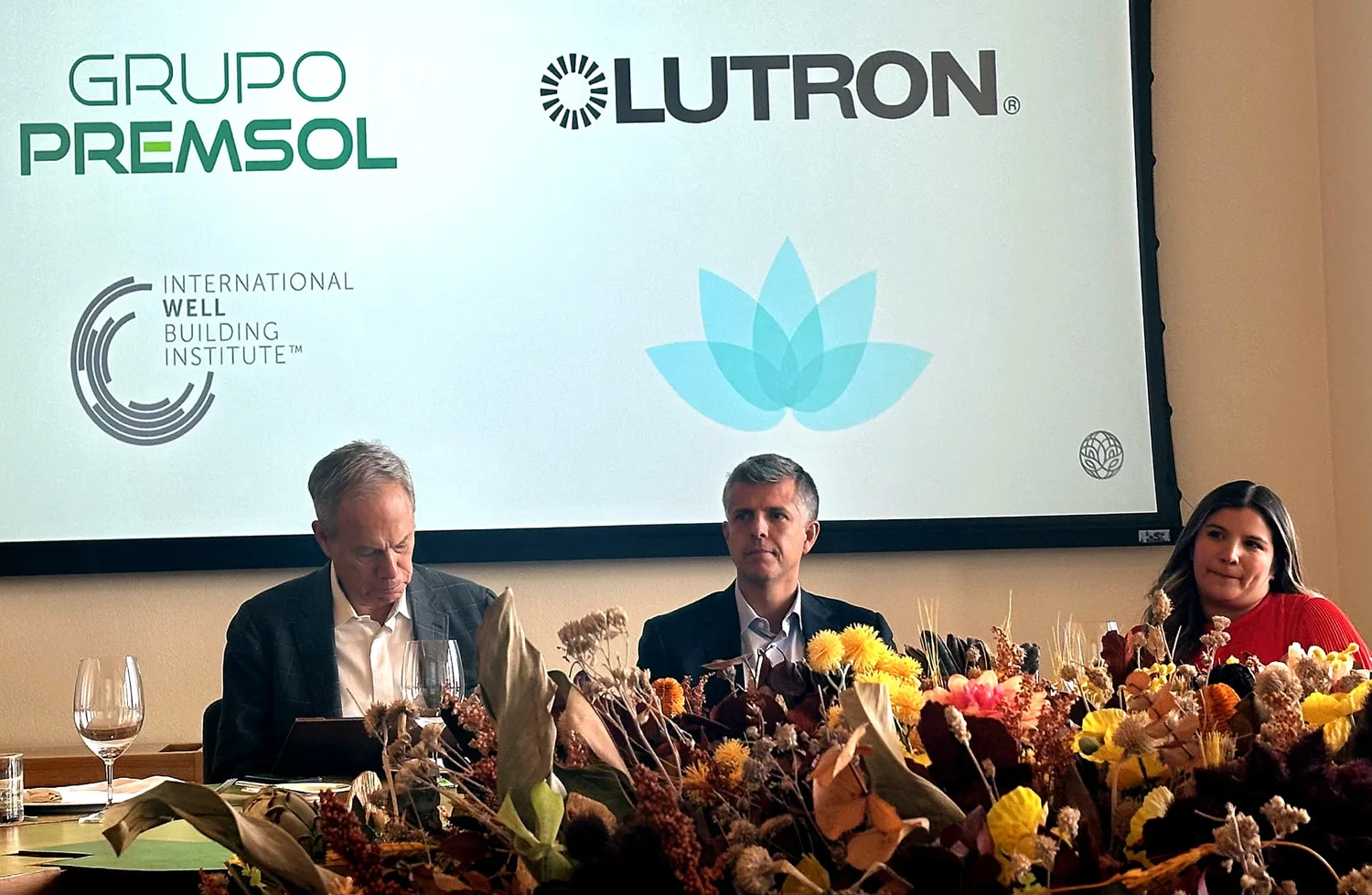 Asistentes sentados en la mesa redonda bajo una pantalla con las marcas de los socios — Grupo Premsol, Lutron, el International WELL Building Institute y 3Lotus — en la sesión inaugural de WRE Circle en la Ciudad de México